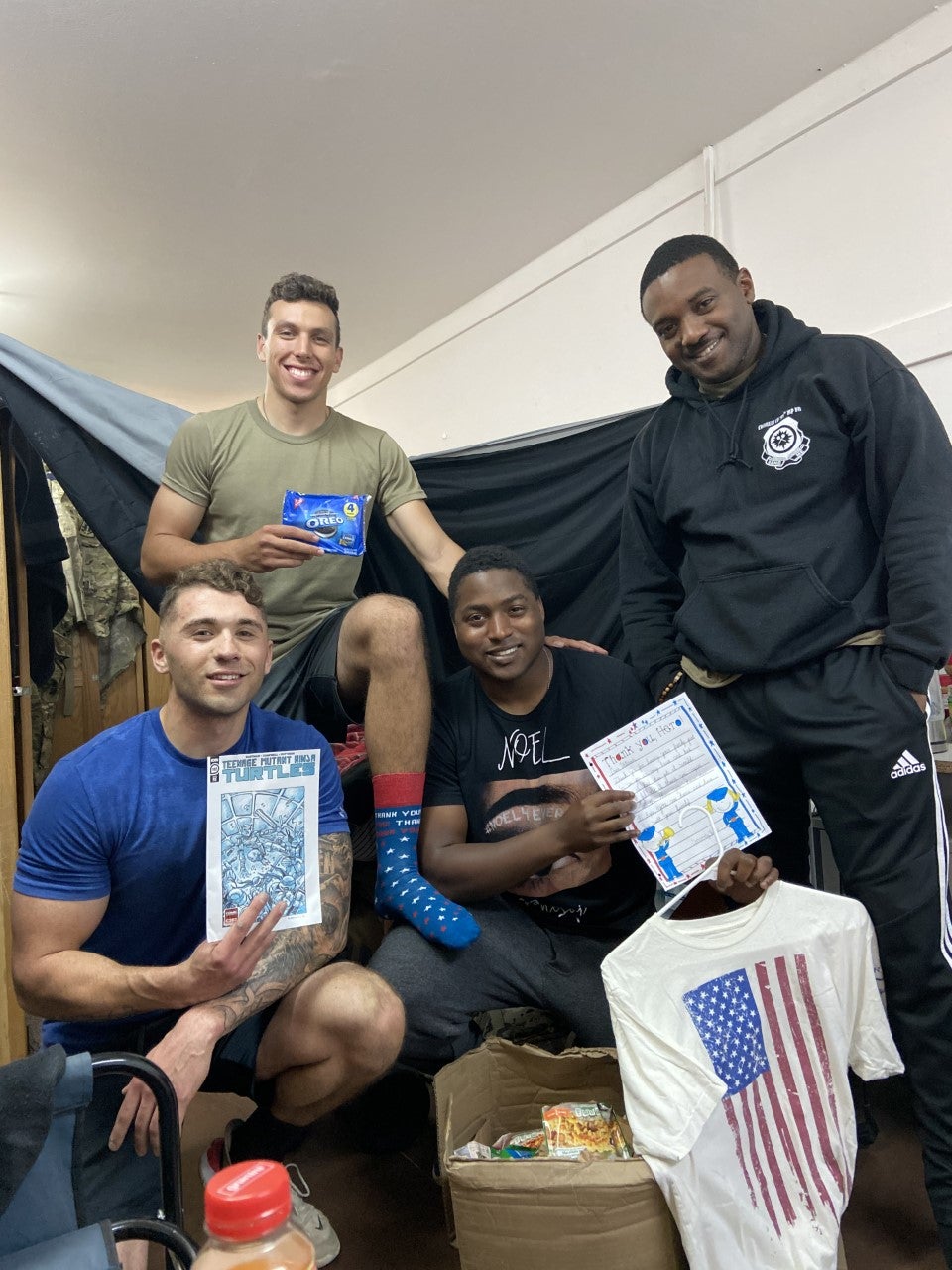 Four soldiers posed with a stack of comics and snacks