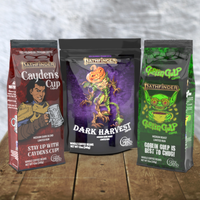 Geek Grind Coffee bags. Dark Harvest roast and cub with a pumpkin headed scarecrow, Cayden's Cup roast with Pathfinder Iconic Valeros on the bag, and Goblin Gulp roast with a green goblin on the bag