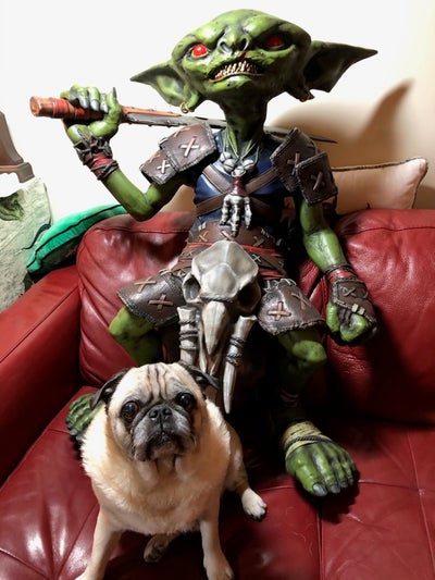 Model of a live sides goblin statue sitting behind a pug