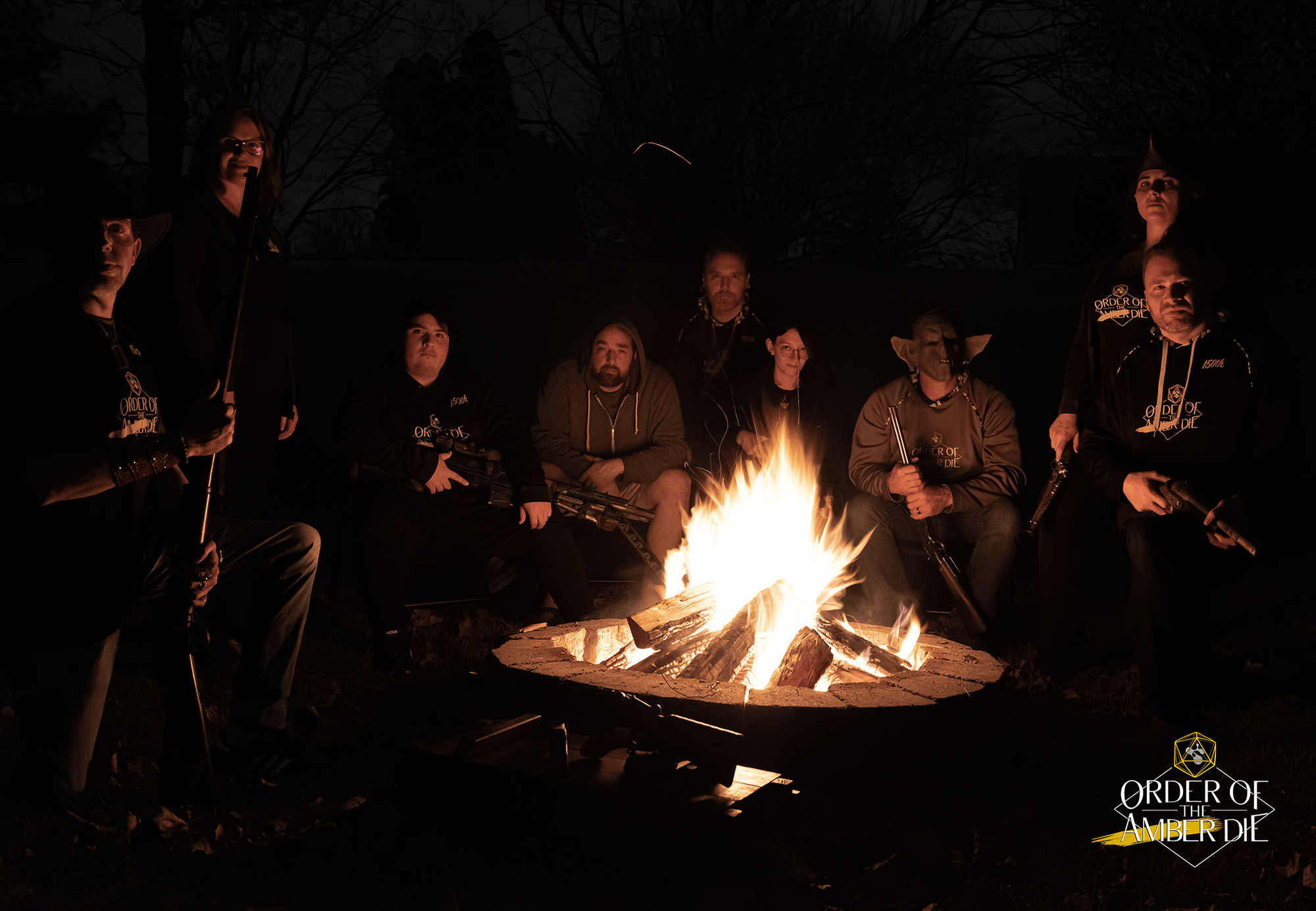 A group of people sitting in the dark around a lit camp firex