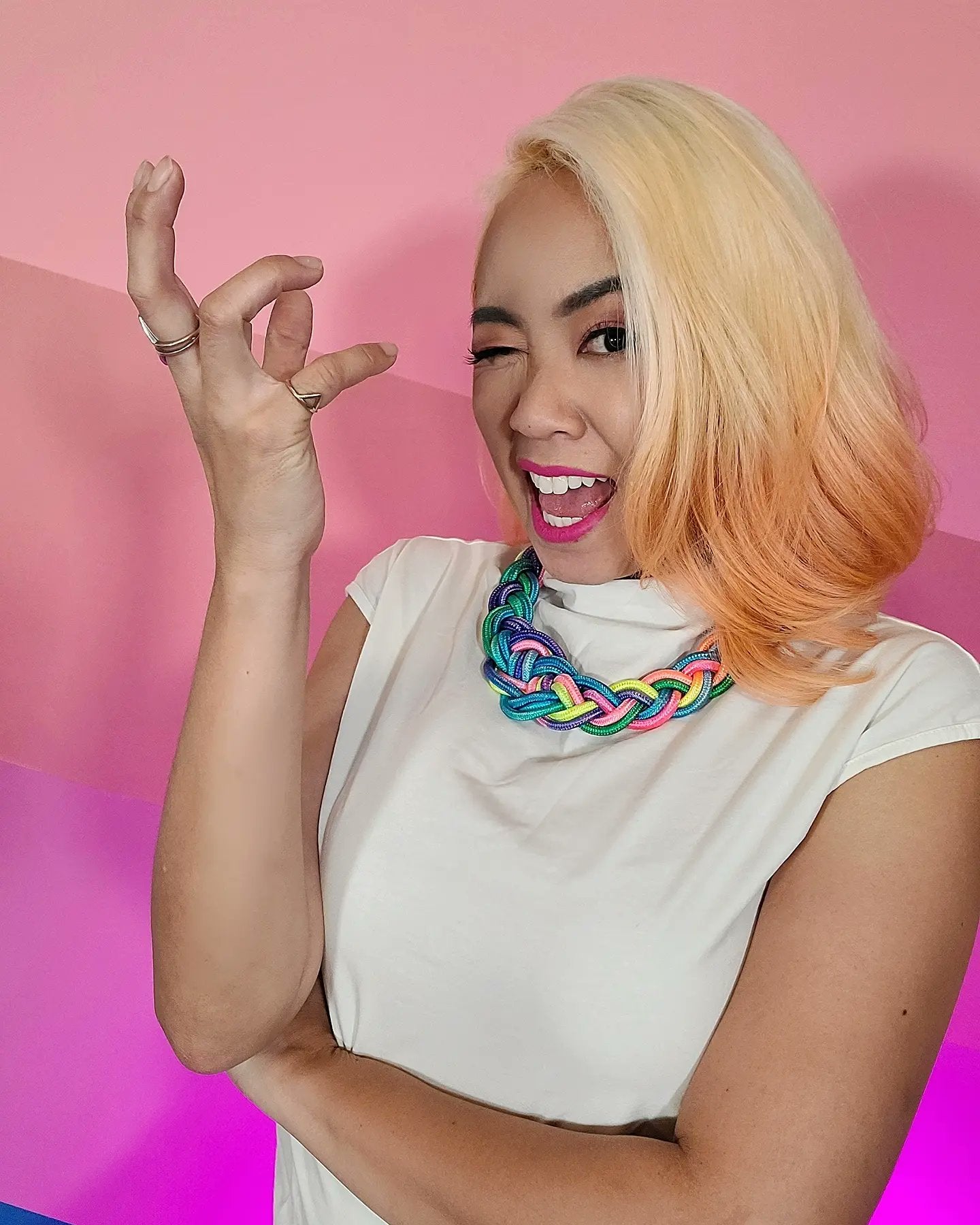 Headshot of Michelle Nguyen Bradley, she stands in front of a pink gradient background make gesturing dramatically