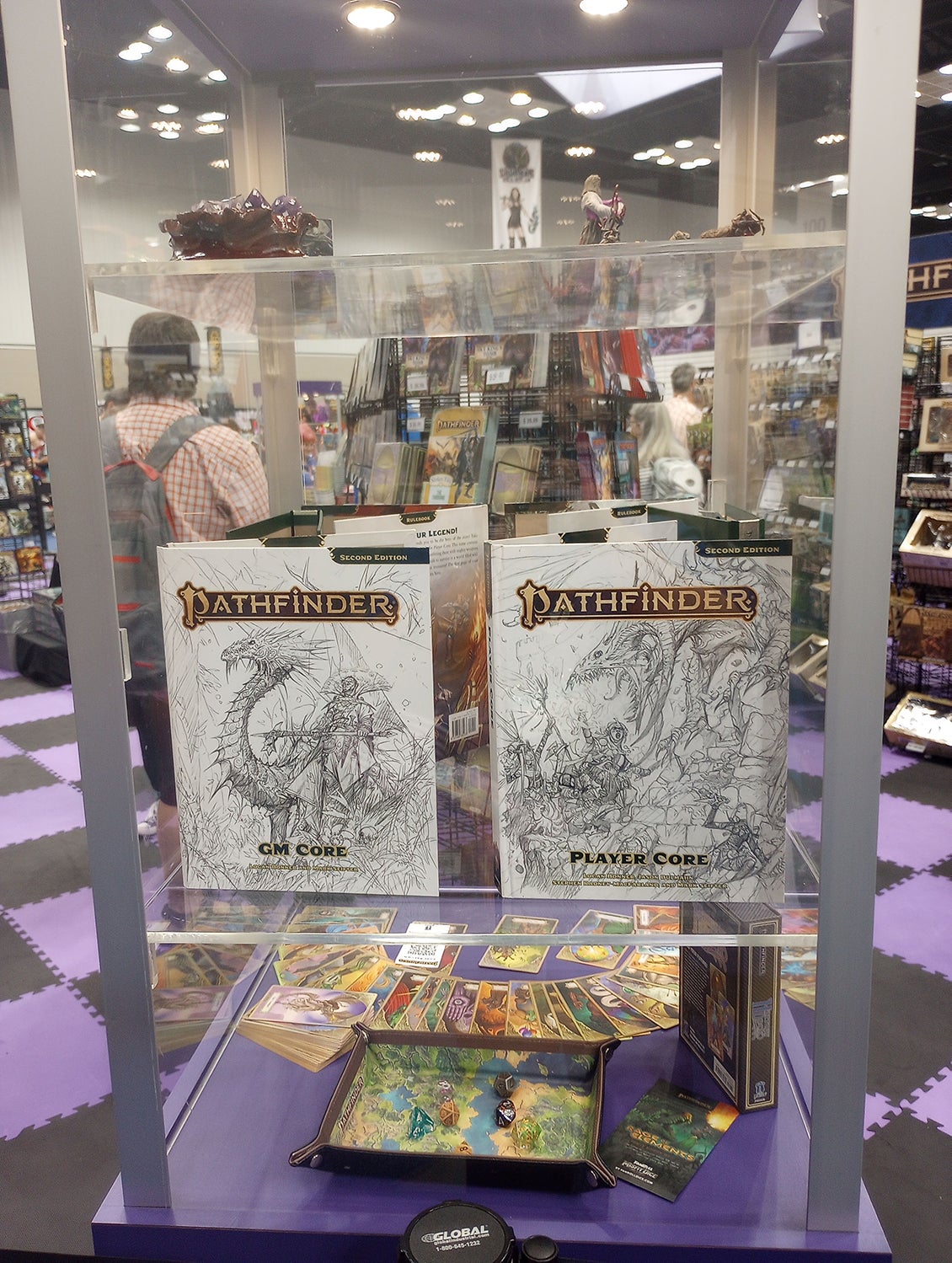 A show case at the Paizo Booth featuring the sketch covers of the Pathfinder Second Edition Remaster GM Core and Player Core