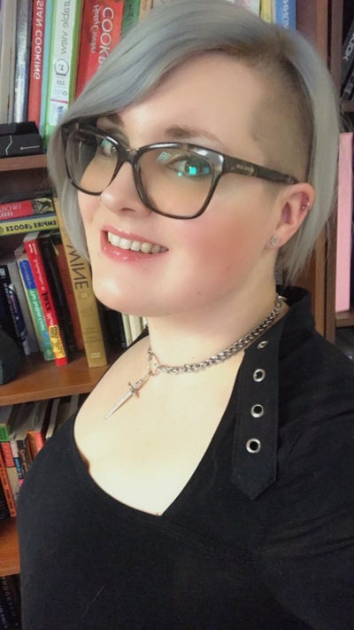 Headshot of Jenny Jarzabski wearing a black blouse and standing in front of a bookshelf
