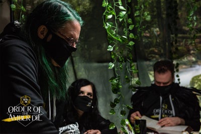 Three players, all masked, leaning over the table.