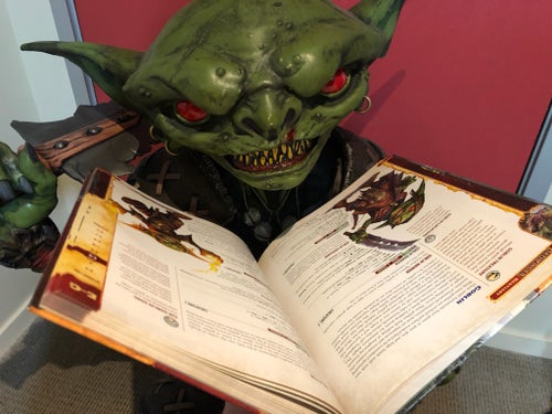 Life sized goblin statue with a book open in front of it to give the appearance of reading
