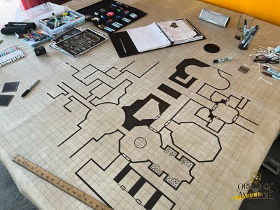 A photo of a large roll of butcher paper with a square tiled map drawn in black pen. The map appears to be a draft of a potential table top dungeon.