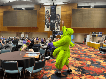 A person dressed in a Skittermander cosplay tossing miniatures to players
