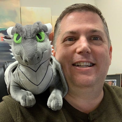 Jim Butler with a grey plush dragon on his shoulder