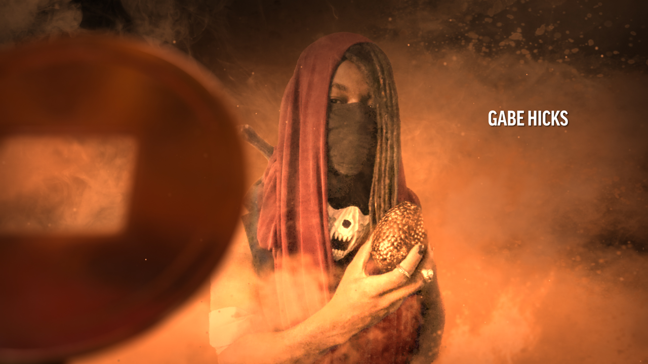 Gabe Hicks, a man standing in orange smoke with a robe over his head and a scarf covering his face, holding a golden egg