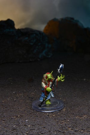 Mini figure of an Orashu Headteacher, a green alien with a snail-like face, holding a staff