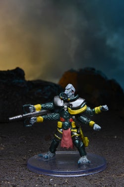 Mini figure of the four-armed giant Shobhad, wearing a black and green padded suit with a large gun in one hand