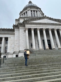 Director of Sales, Cosmo Eisele carrying a box full of games up the steps of the Washington state capitol building
