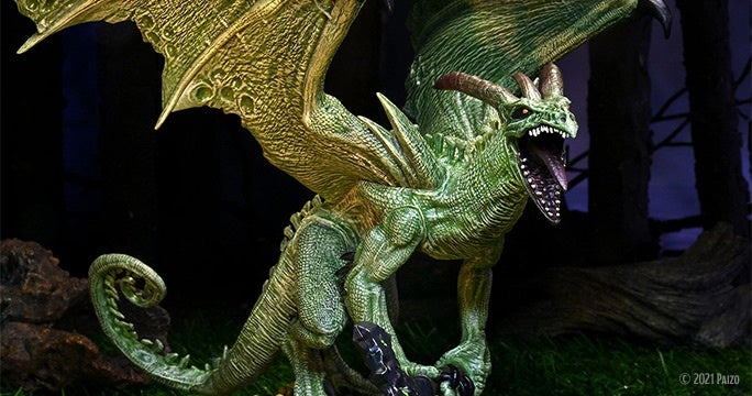 Mini figure of pathfinder deity Treerazer, staged in a darkly lit forest background