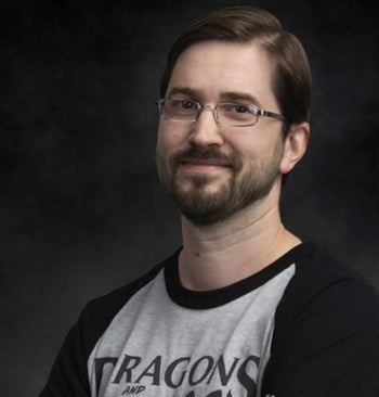 Headshot of Jim Rodehaver, standing in front of a dark background wearing a Dragons and Things t-shirt