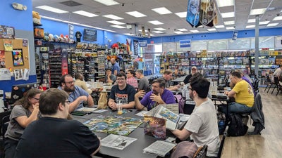 A hobby and gaming shop with multiple tables full of players playing Pathfinder or Starfinder